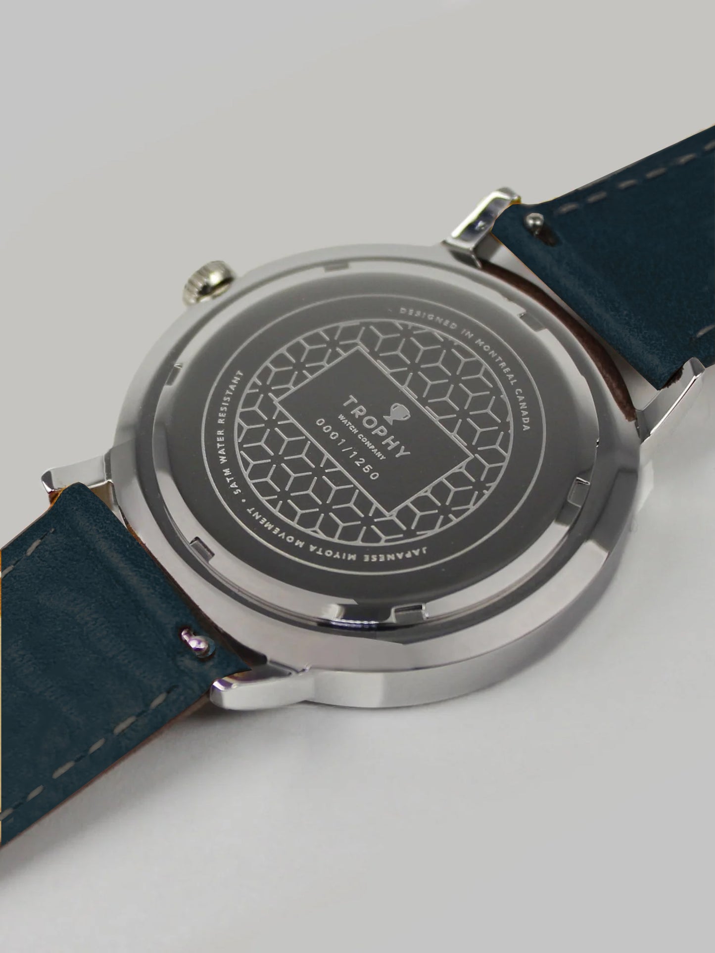 Trophy Watch Company | 40mm EMBERLINE PERLON: The Emerline Perlon brings an air of sporty sophisticaion to anyone who wears it. Truly unique in design and appearance, this watch makes a strong statement. The perlon strap has cords of navy blue, grey, teal