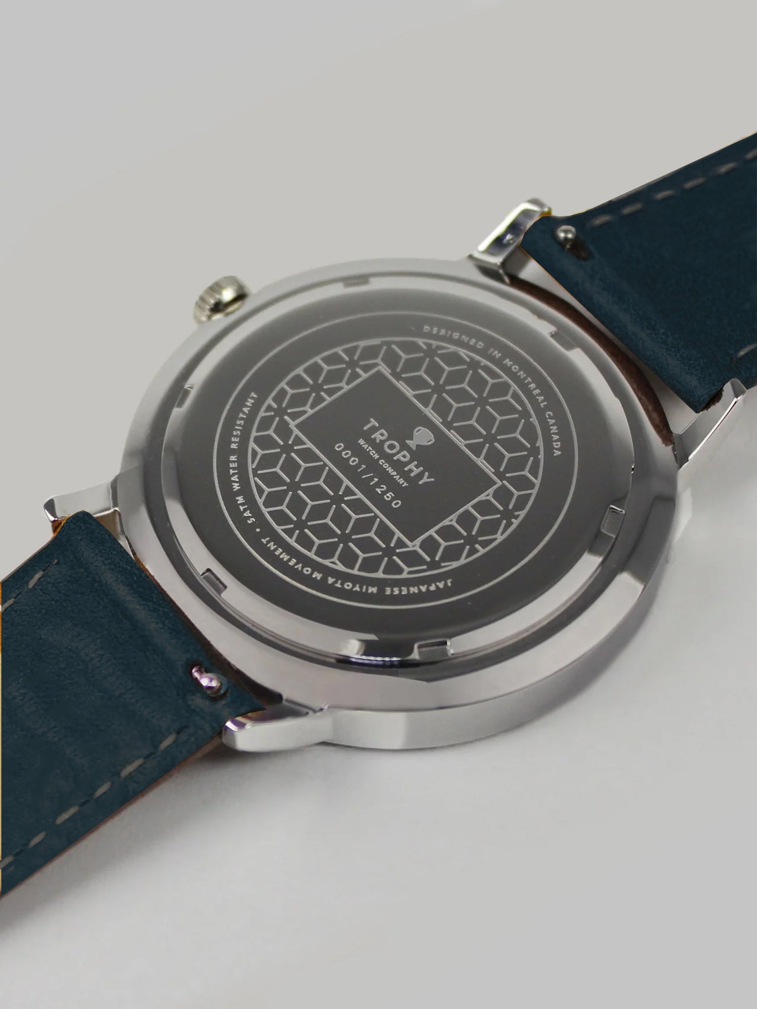 Trophy Watch Company | 40mm EMBERLINE PERLON: The Emerline Perlon brings an air of sporty sophisticaion to anyone who wears it. Truly unique in design and appearance, this watch makes a strong statement. The perlon strap has cords of navy blue, grey, teal